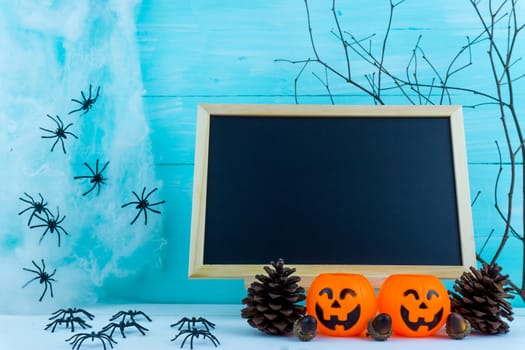Halloween holiday background with spider, webs, blackboard and jack lantern on blue wooden table with copy space for text. Flat lay, top view