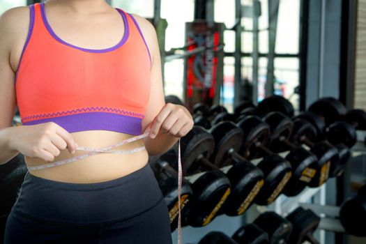 Fat woman hand holding excessive belly fat with measuring tape.  Diet, weight loss, slim body, healthy lifestyle concept.