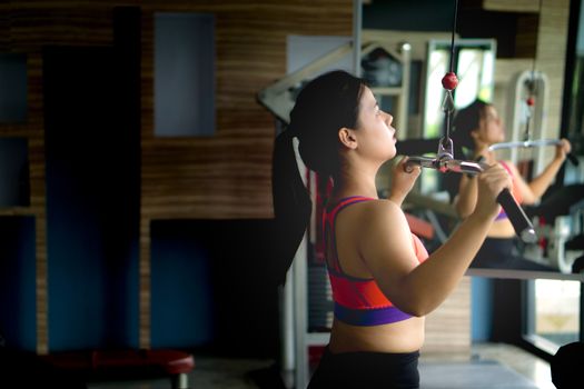 Asian beauty woman doing exercise for back. Working out on a lat pulldown machine. Diet, weight loss, slim body, healthy lifestyle concept.