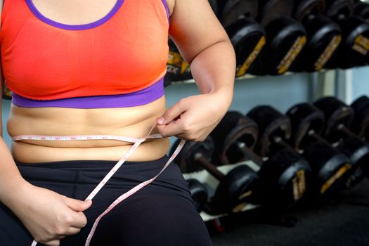 Fat woman hand holding excessive belly fat with measuring tape.  Diet, weight loss, slim body, healthy lifestyle concept.