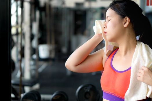 Asian beauty woman wiping sweat with towel at fitness gym.  Diet, weight loss, slim body, healthy lifestyle concept.