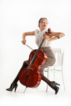 Young woman playing on a cello on an isolated studio background
