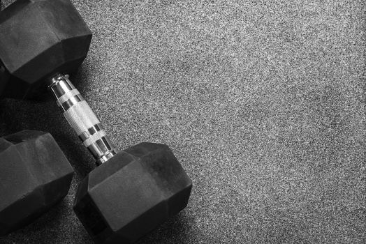 Two black dumbbells on a wooden gray in the gym