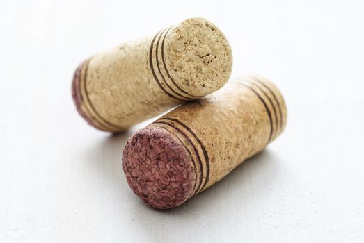 Close-up of several used red wine bottle corks sitting on white surface