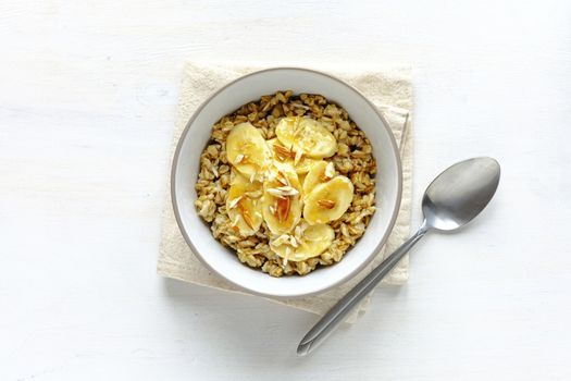 Flat lay view of oatmeal with banana in bowl against white table