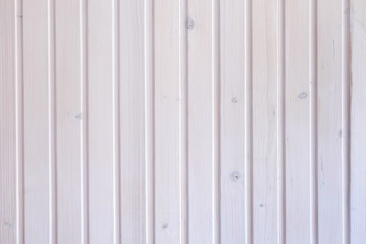 Background texture of a white painted wooden wall with knots and vertical planks in a full frame view