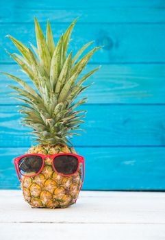 Holiday pineapple have sunglasses on blue wooden background, tropical holiday concept