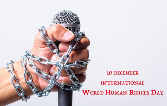 Hand holding microphone and have chain on fist hand with 10 december international world HUMAN RIGHTS DAY text on white background, Human rights day concept