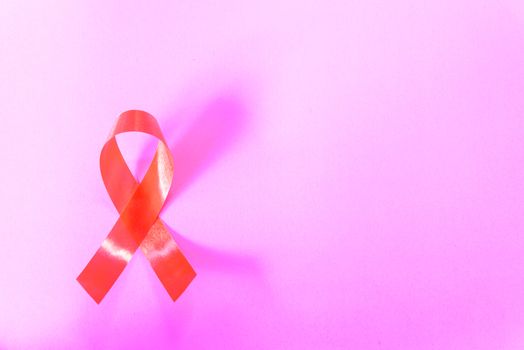 Red Ribbon Support HIV, AIDS on pink background and copy space for use