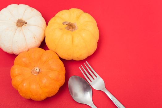 Halloween and Thanksgiving day pumpkins and leaves on red background with copy space for use