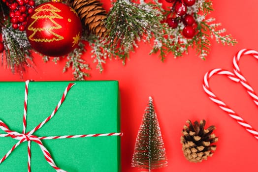 Christmas green gift box and decorations, fir tree branches on red background. Merry Christmas concept. With Copy space for text
