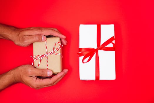 Happy New Year and Christmas 2020 or valentine day, top view hands with Brown gift box on red background with copy space for your text