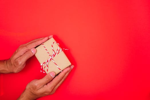 Happy New Year and Christmas 2020 or valentine day, top view hands with Brown gift box on red background with copy space for your text