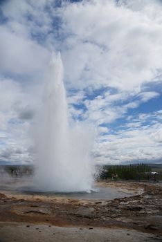 Strokkur geyser eruption in Iceland with blue sky and clouds