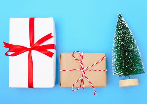 Happy New Year and Christmas 2020 or valentine day, top view craft paper wrapped present gift box craft and fir tree on blue background with copy space for your text