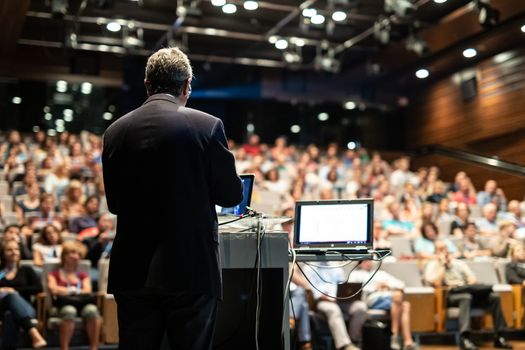 Speaker giving a talk on corporate business conference. Unrecognizable people in audience at conference hall. Business and Entrepreneurship event.