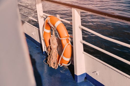 Red Lifebuoy in front of the blue sea and the white ship