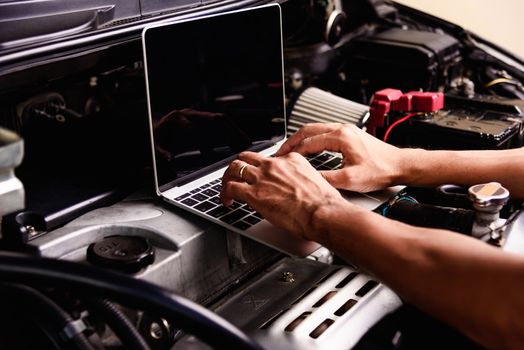 Professional car repair or maintenance mechanic engine working service with laptop computer at workshop