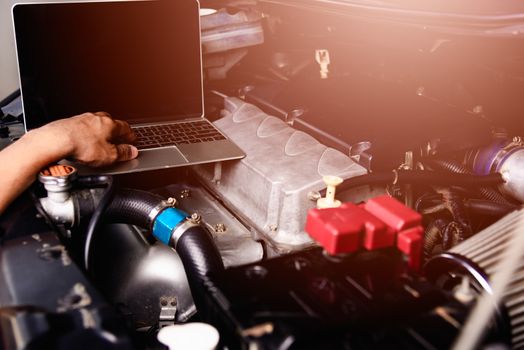 Professional car repair or maintenance mechanic engine working service with laptop computer at workshop