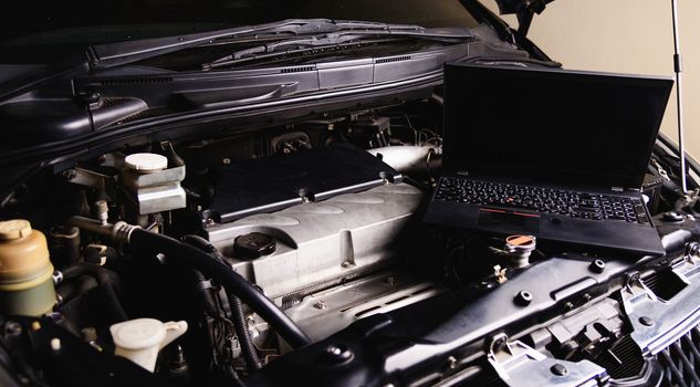 Laptop computer on car mechanic engine for service at workshop