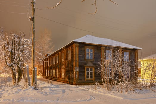 Winter street in night illumination with an old house in the foreground