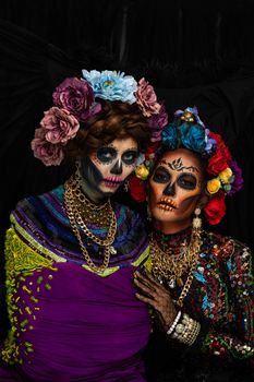 Closeup portrait of women with a sugar skull makeup dressed with flower crown. Halloween concept