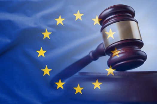 European Union flag with wooden gavel in close-up full frame background concept, symbolising legal verdict in court