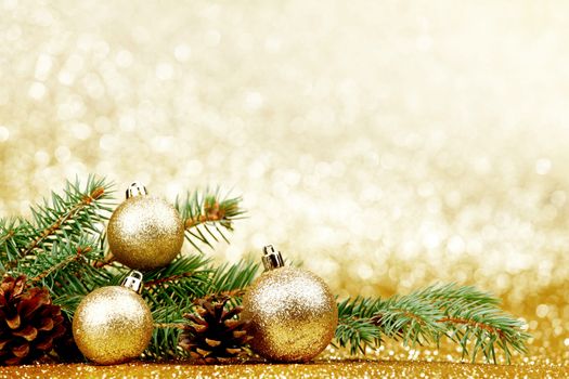 Christmas card with fir tree branch and decoration on golden glitter background