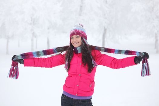 Happy smiling girl in pink clothes having fun in winter park