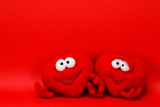 Two wool red hearts on red background with copy space for text, symbol of love, healtcare, valentines day concept