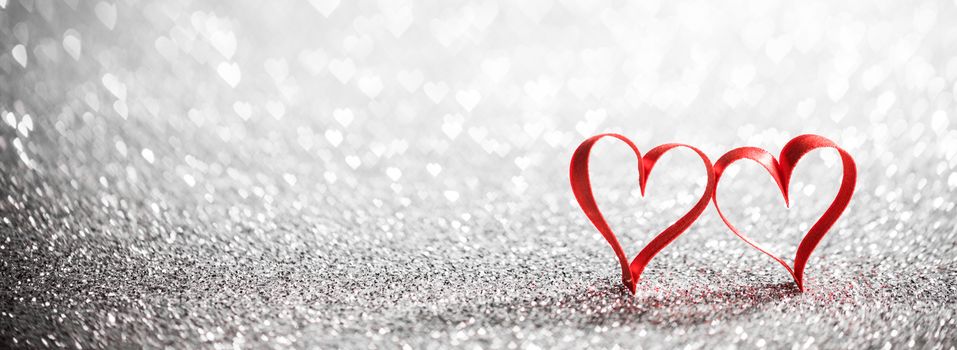 Two red ribbon hearts on glitter background with copy space for text, Valentines day concept
