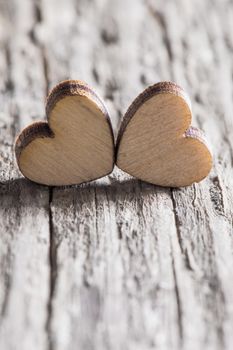 Two handmade wooden carved hearts on light wood background couple relationship Valentine day concept