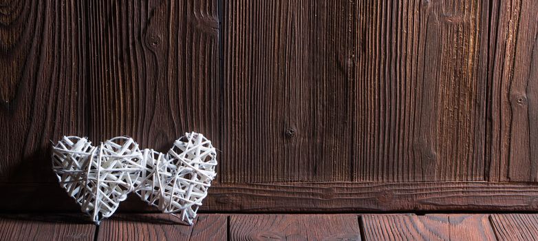 Two wicker hearts on wooden background with copy space for text