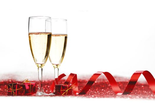 Glasses with Champagne and gifts on red glitters isolated on white background