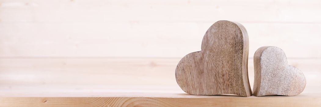 Two handmade wooden carved hearts on light wood background couple relationship Valentine day concept