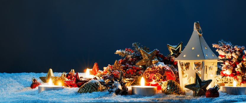 Christmas composition of lantern colorful ornaments balls stars candles and fir tree branches on snow