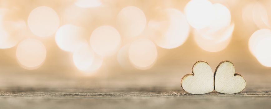 Two handmade wooden hearts on beautiful golden bokeh background. Vintage style. Love Valentine's Day concept.