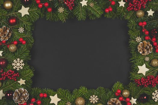 Natural fir Christmas tree border frame with decor on black, copy space for text