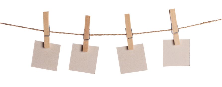 Set of four blank paper notes held on a string with clothespins isolated on white background