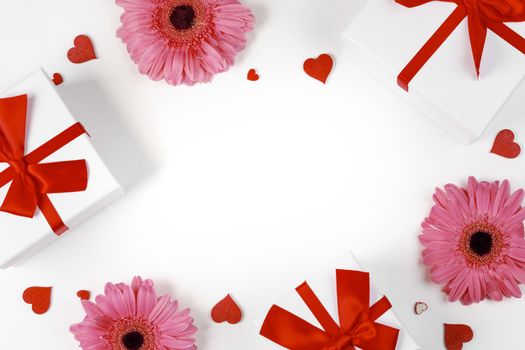 Pink gerbera flowers gifts and red hearts composition on white background top view with copy space. Valentine's day, birthday, wedding, Mother's day concept. Copy space