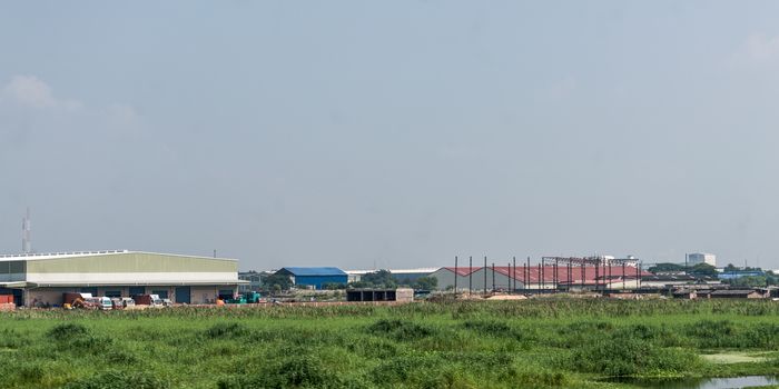 Industrial site power plant landscape. Industry surrounded by rural agricultural field and green summer meadow. A beautiful non-urban scenic environment of Rural Countryside of India, south asia pac.