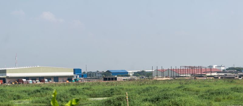 Industrial site power plant landscape. Industry surrounded by rural agricultural field and green summer meadow. A beautiful non-urban scenic environment of Rural Countryside of India, south asia pac.