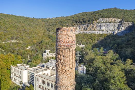 an aerial view of abandoned factory with chimney in forefront in Raša, Croatia