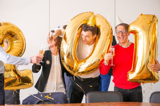 Business people are celebrating holiday in modern office drinking champagne and having fun in coworking. Merry Christmas and Happy New Year 2020 concept