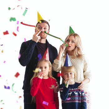 Family blowing party trumpets with confetti celebrating new year