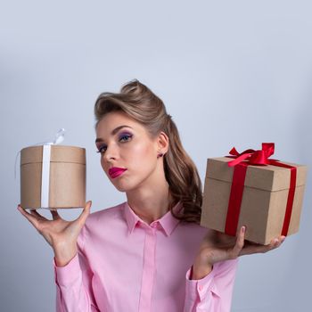 Young happy woman puts her ear to holiday presents with bows