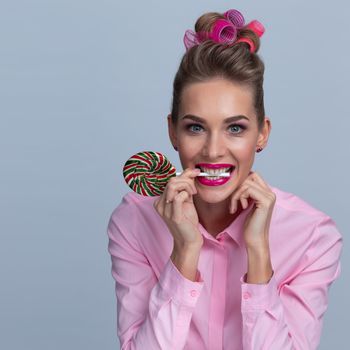 Pretty woman in hair curlers getting ready for Christmas New Year party holding big lollipop