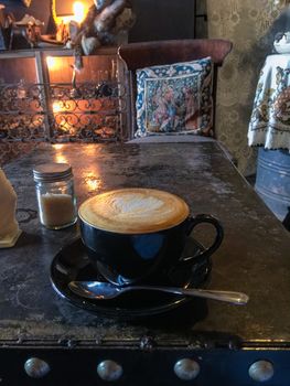 Coffee Time peple in cafe. Coffee black cup with milk and heart shape. Hot mocha coffee or capuchino in the black cup with heart pattern leather on the table. Beverage, full. Thai coffee. In Thailand.