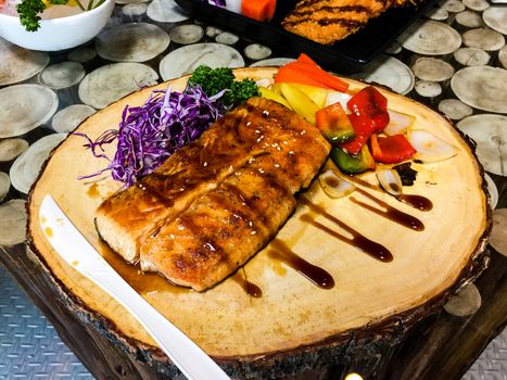 Grilled salmon steak slices on wooden cutting board, Cabbage, bell pepper, pineappleม White sesame.