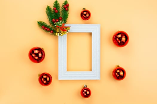Christmas holidays composition, top view of red Christmas decorations and picture frame on yellow background with copy space for text. Flat lay, winter, postcard template, new year concept.